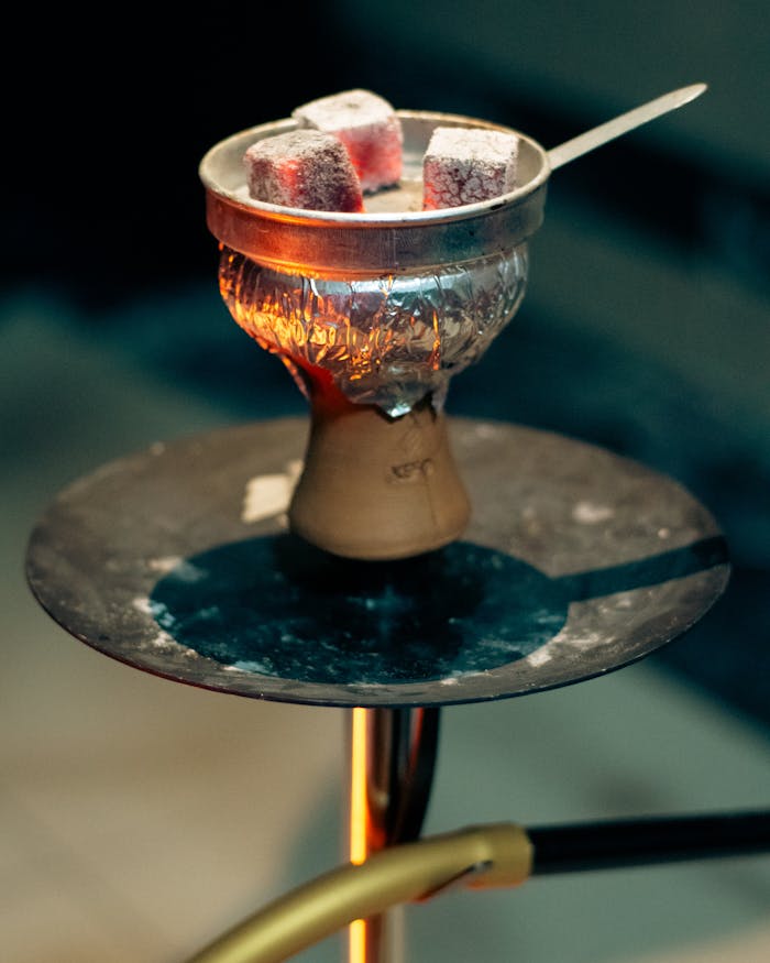 A detailed shot of a hookah with glowing charcoal on a stand, showcasing intricate design elements.