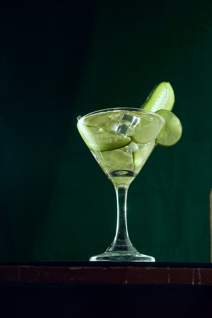 Elegant cocktail with green garnish in a stylish glass against a dark background.