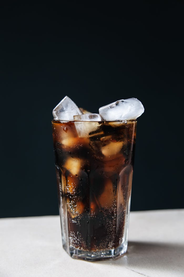 Services Refreshing glass of cola with ice cubes against a dark background, perfect for summer.